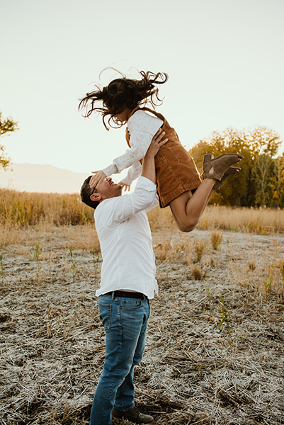 Family standing together during an outdoor lifestyle family photoshoot in a field in Utah at sunset.