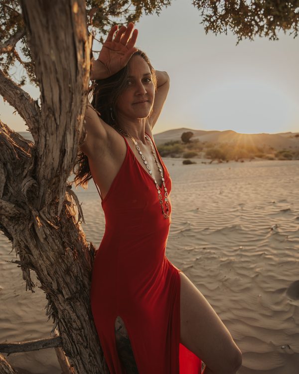 a woman in a red dress in the sand dunes