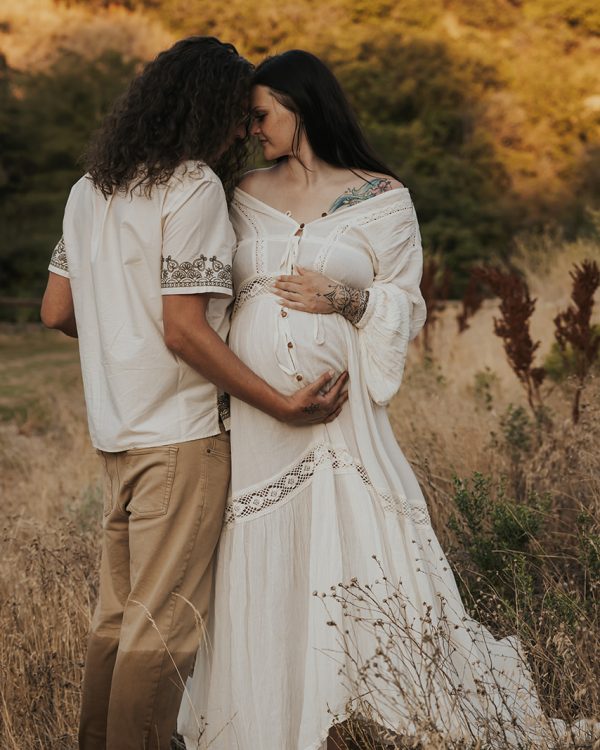 Pregnant woman and partner embracing during an outdoor maternity photoshoot in the Utah mountains.