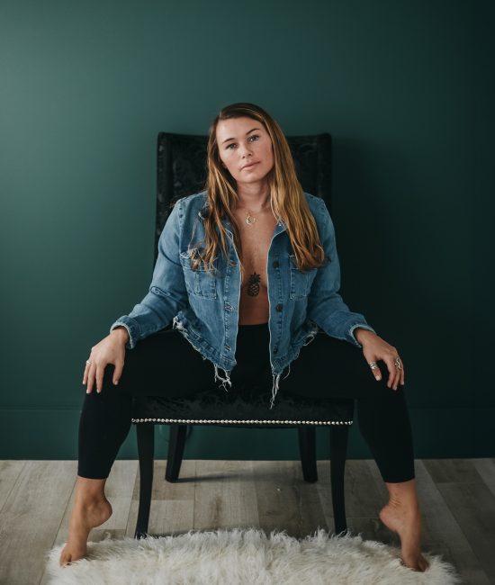 Woman in a studio sitting on a chair with her hands on her knees