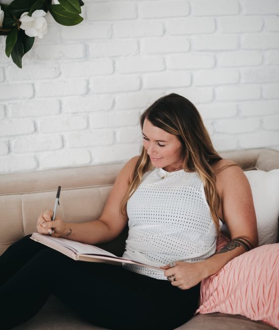a woman on a couch writing in her journal