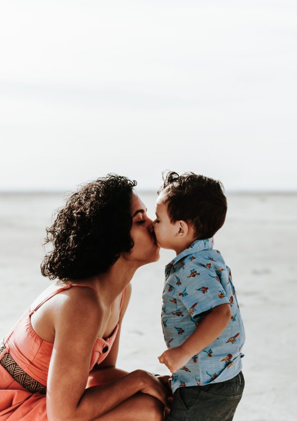 A son giving his mom a kiss during an outdoor lifestyle family photoshoot on the Salt Flats at Dusk.