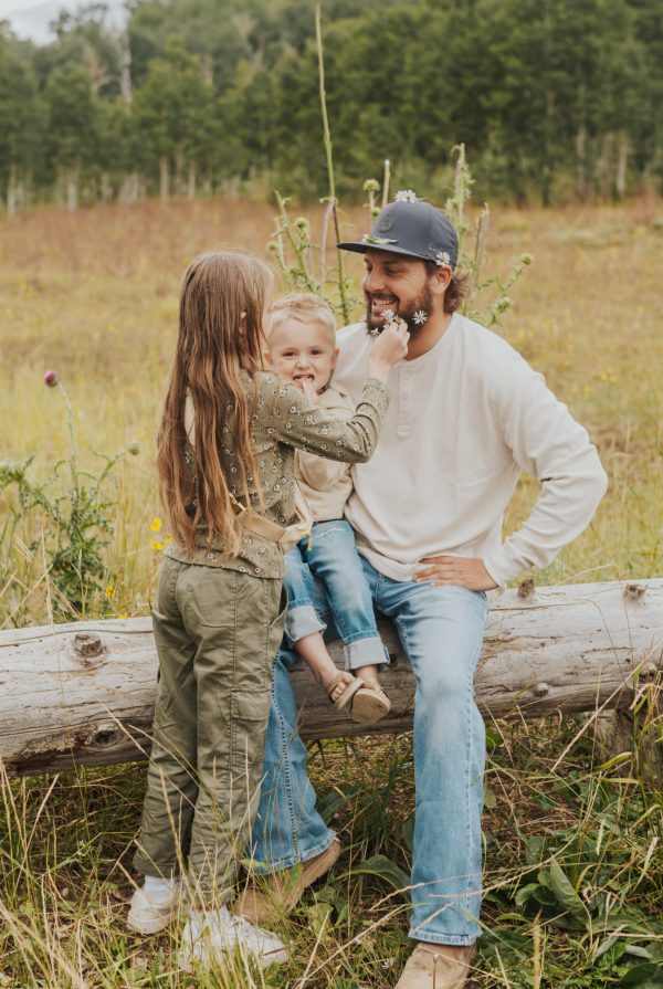 Kids putting flowers in their dads beard during an outdoor lifestyle family photoshoot in the mountains of Utah at sunset.