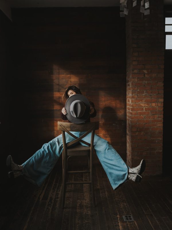 woman in a studio holding a hat having fun