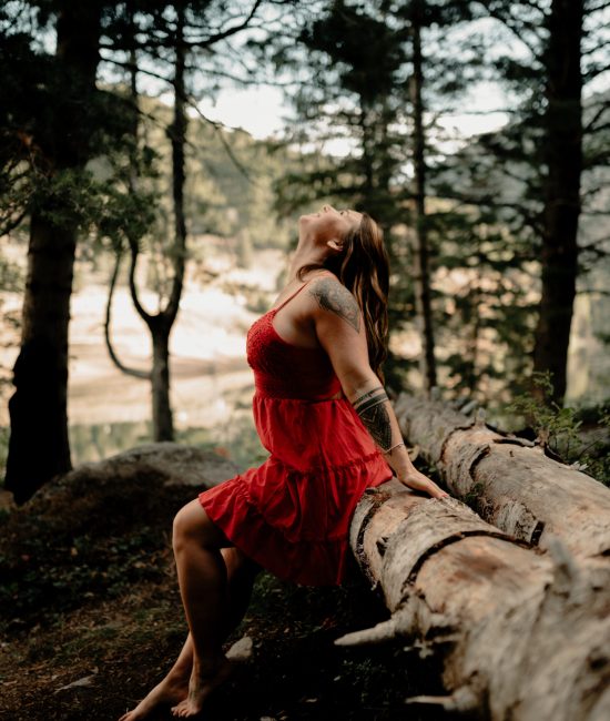 a woman in a red dress stretching her arms out